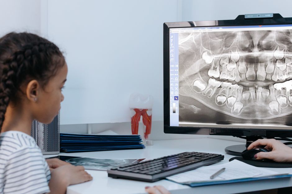 Dentist reviewing a child's dental X-ray during an early orthodontic screening visit