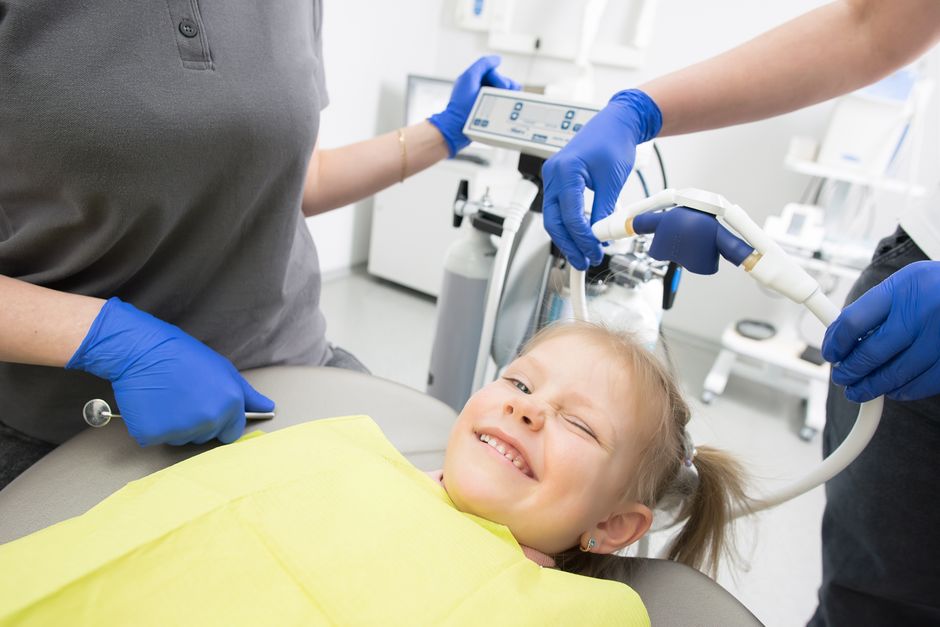 Young child having a dental exam that reflects the rule of 7 in pediatric dentistry screening guideline