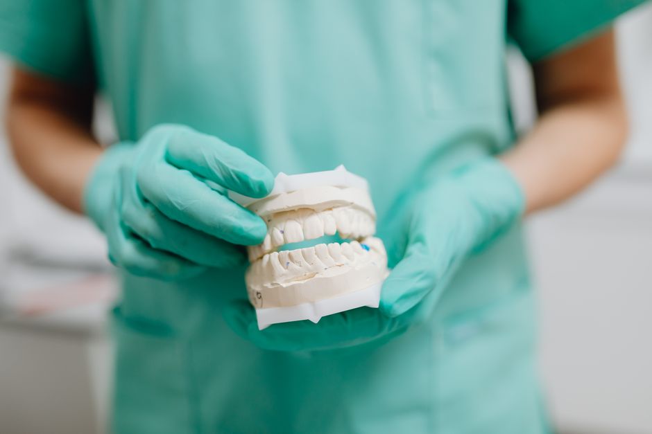 Dentist holding a snap-in denture model showing how it attaches to dental implants