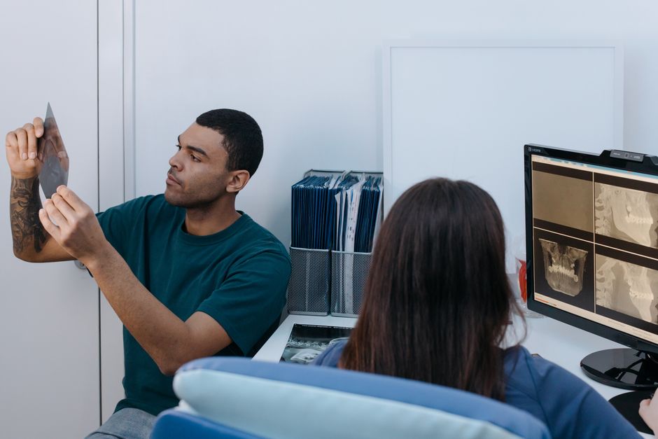 Dentist reviewing a dental implant surgery recovery x-ray with a patient during a follow-up healing check